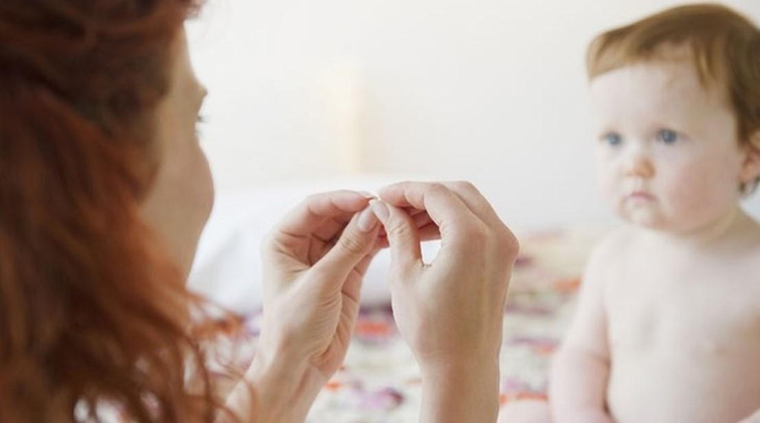 Woman with red hair showing sign language to baby with brown hair